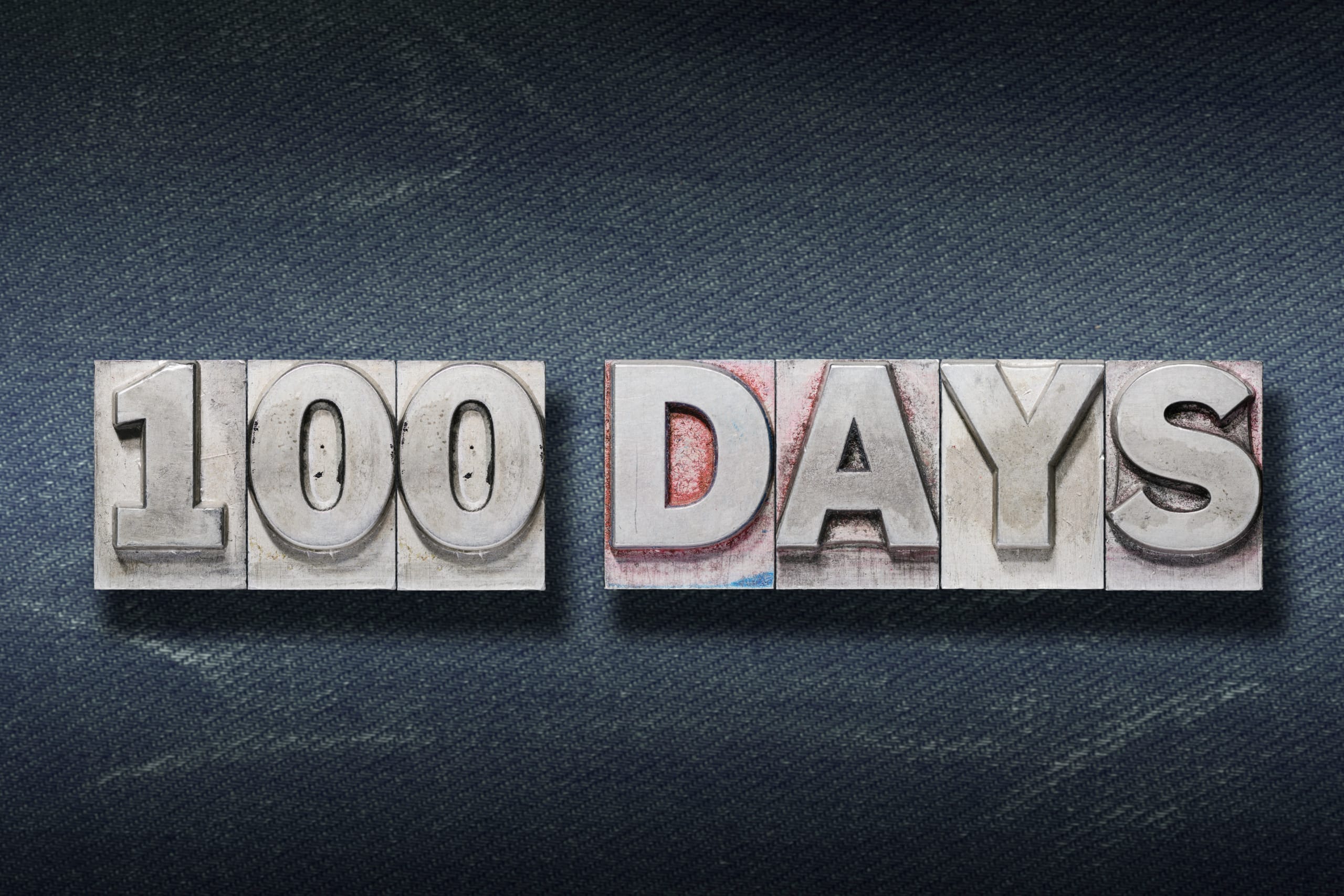 one hundred days phrase made from metallic letterpress on dark jeans background